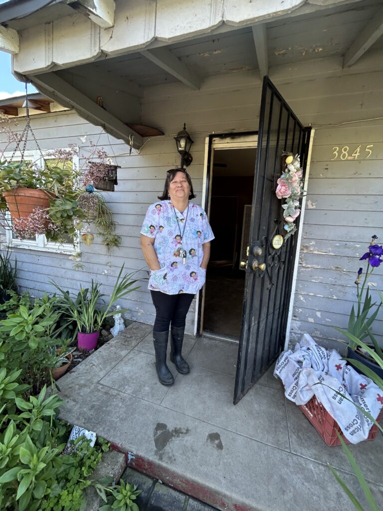 A flood survivor standing in front of her home.